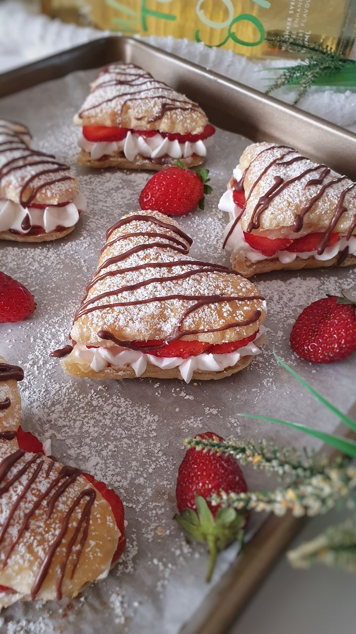 strawberry shortcakes with chocolate drizzled on them and strawberries in the foreground
