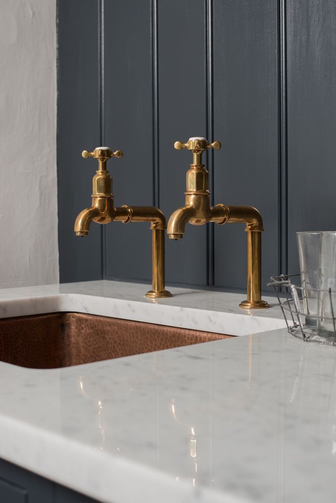 two golden faucets are sitting on the counter in front of a marble sink