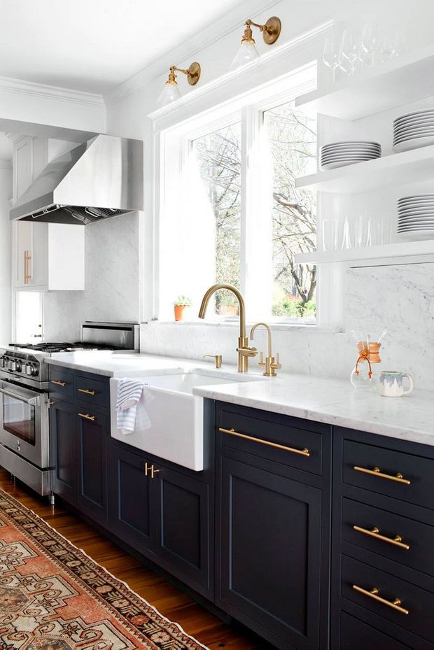 a kitchen with black cabinets and white counter tops, gold pulls on the faucets