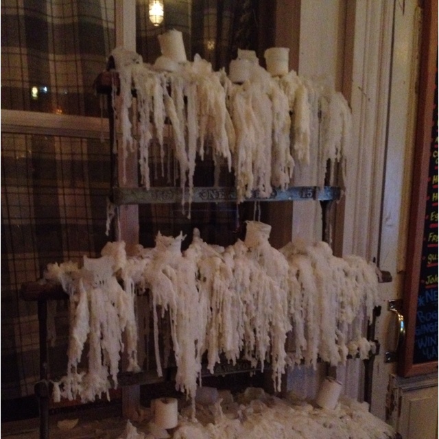 icing is hanging from the ceiling in front of a window with candles on it