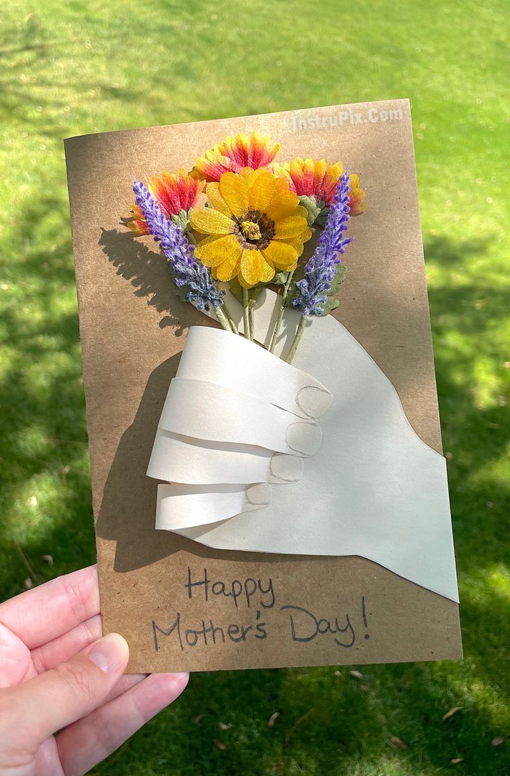 a hand holding up a card with flowers in it and the words happy mother's day written on it