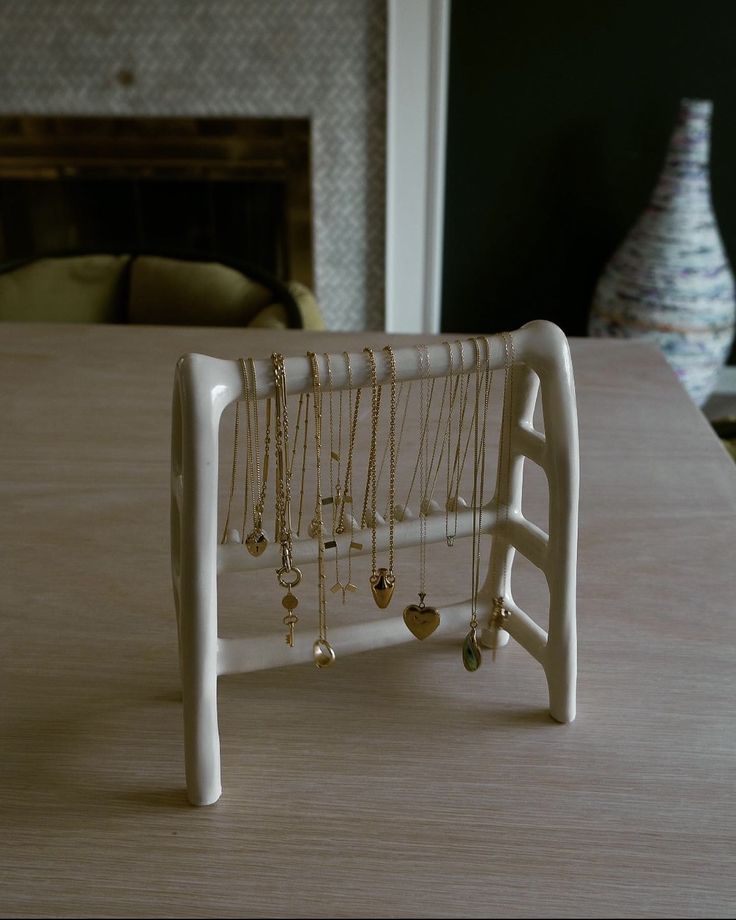 a jewelry rack with necklaces hanging from it on a table in front of a fireplace