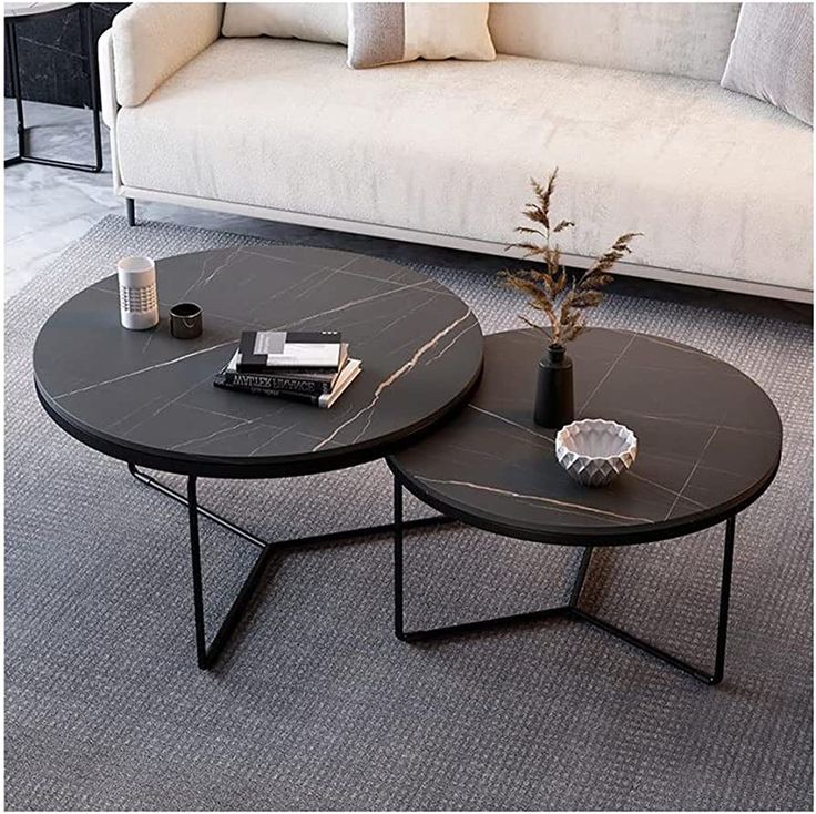 two black tables sitting on top of a carpeted floor next to a white couch