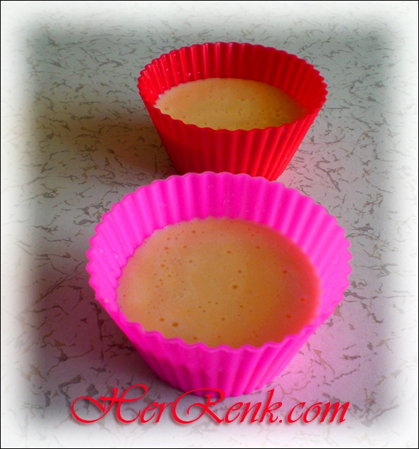 two pink cupcake cases sitting next to each other on a white counter top with red paper liners