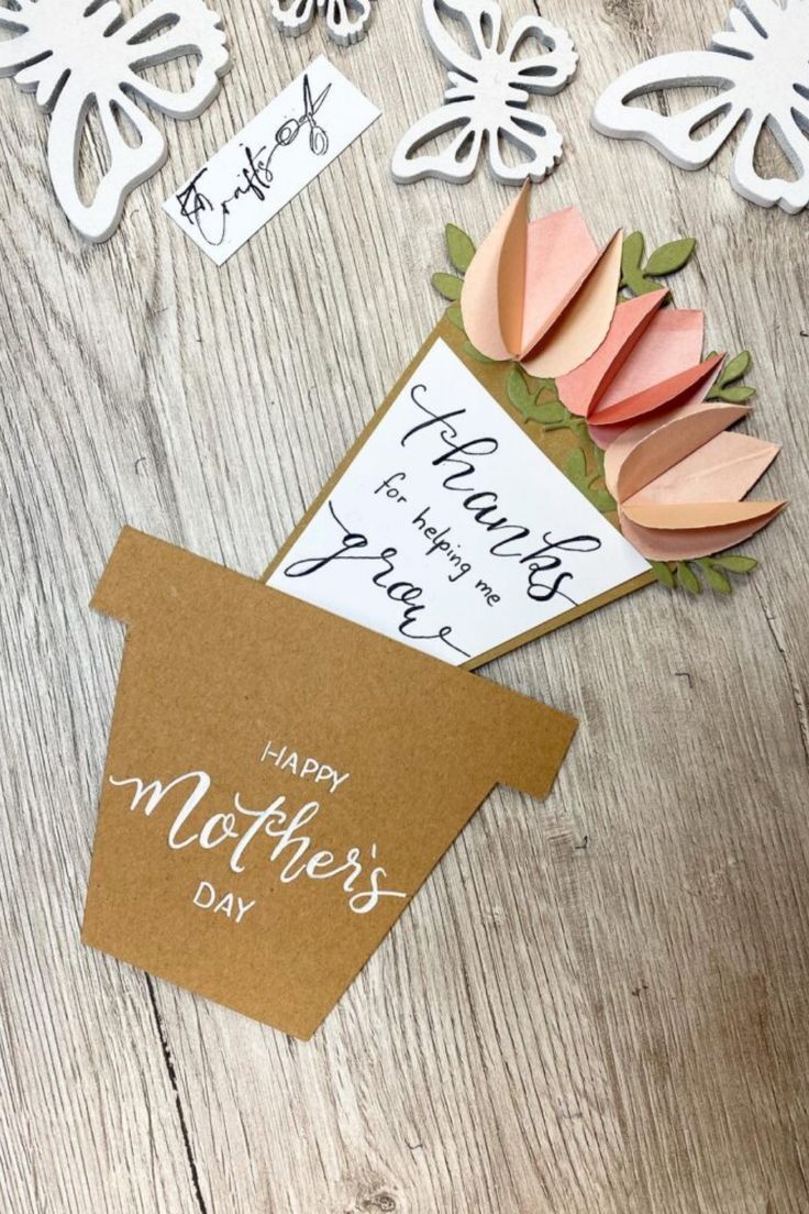 some paper flowers and cards on a wooden table with the words happy mother's day