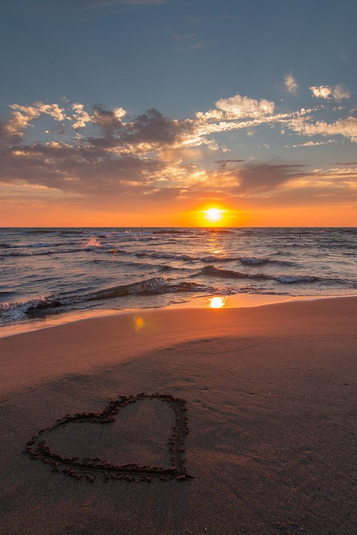 a heart drawn in the sand on a beach at sunset with an inspirational message written below