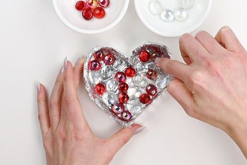 two pictures showing how to make a heart out of candy wrappers and other things