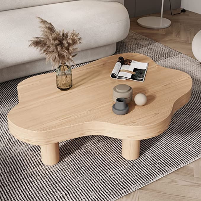 a wooden table sitting on top of a rug next to a white couch in a living room