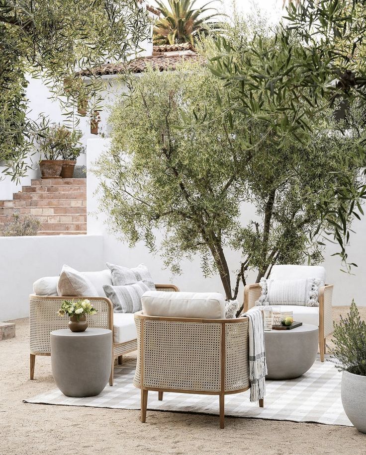 an outdoor living area with white furniture and trees