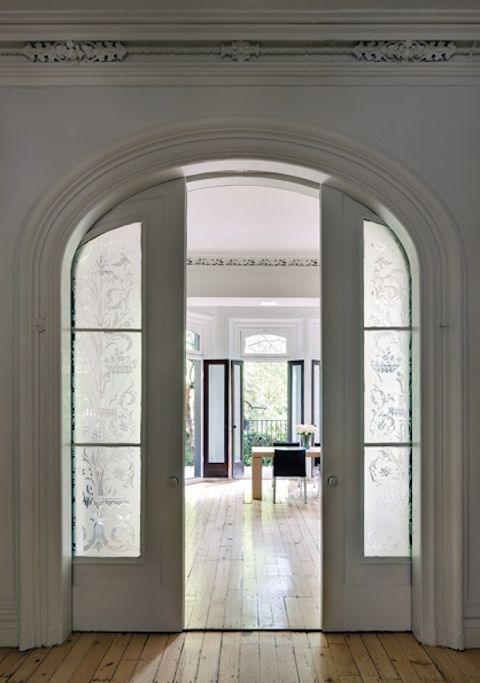 an open door leading into a living room with wood floors and white trim on the walls