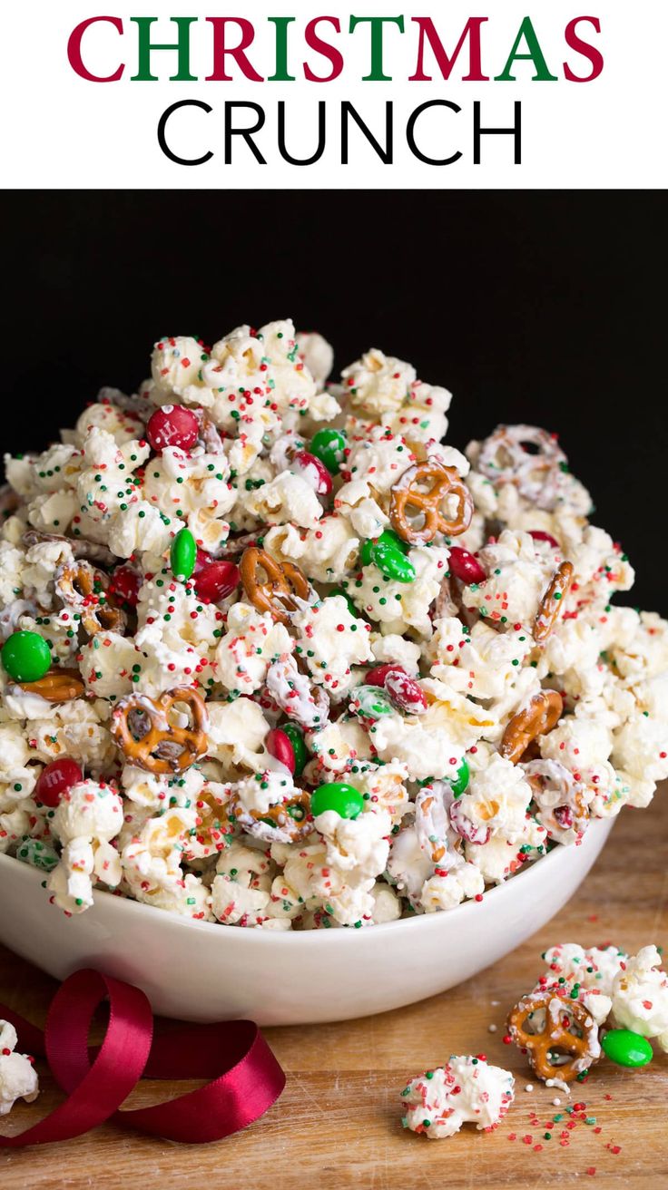 a white bowl filled with christmas popcorn and sprinkles next to a red ribbon