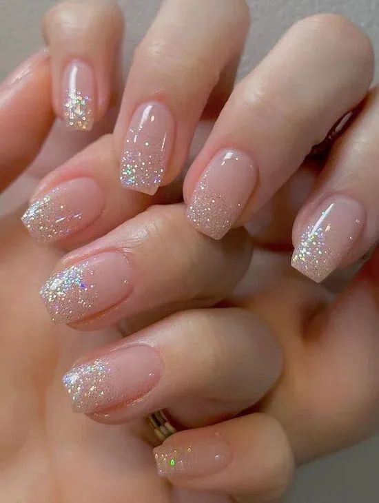 a woman's hand with long, shiny nails and gold glitters on it