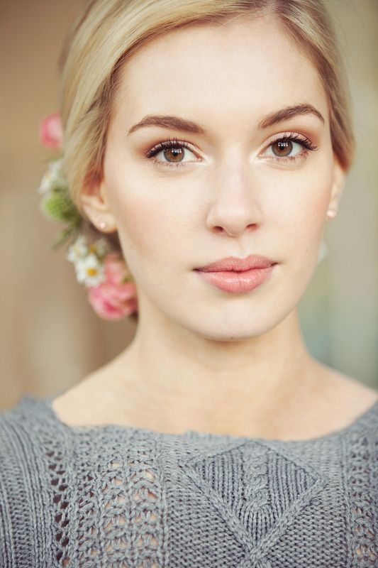 a woman with flowers in her hair wearing a gray sweater and flower in her hair