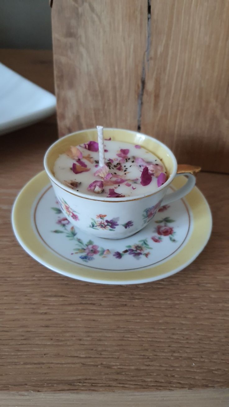a teacup filled with flowers on top of a saucer and plate next to a wooden block
