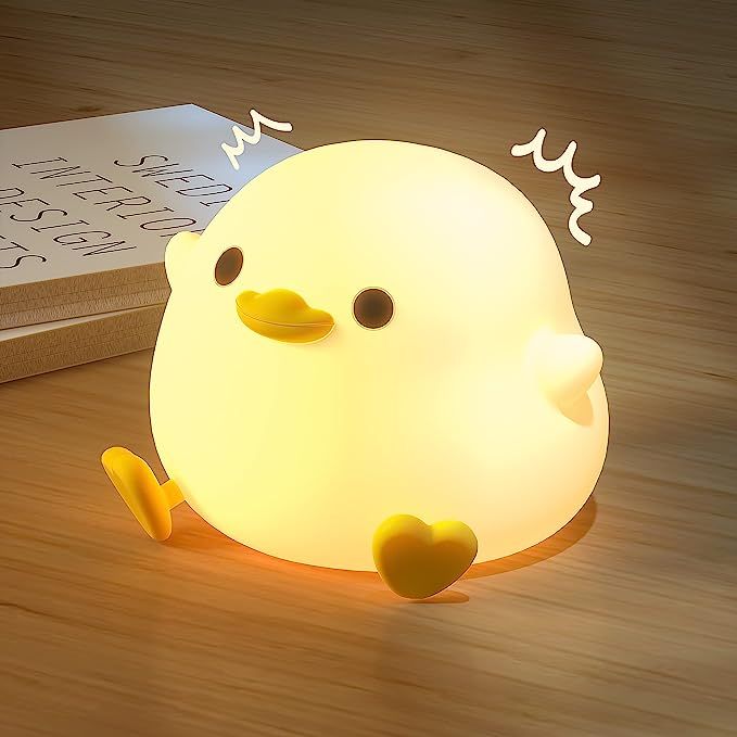 a yellow ducky night light sitting on top of a wooden table next to a book