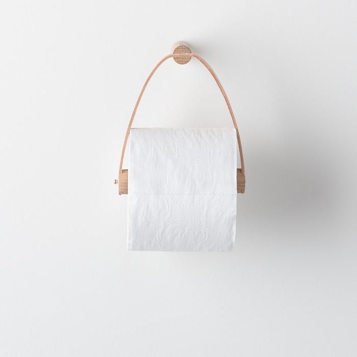 a roll of toilet paper hanging from a rope on a wall with a wooden holder