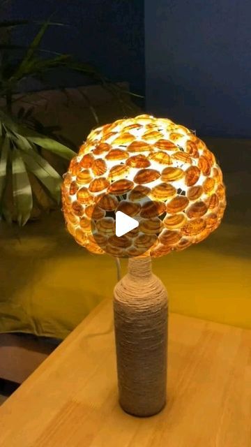a lamp that is sitting on top of a wooden table in front of a plant