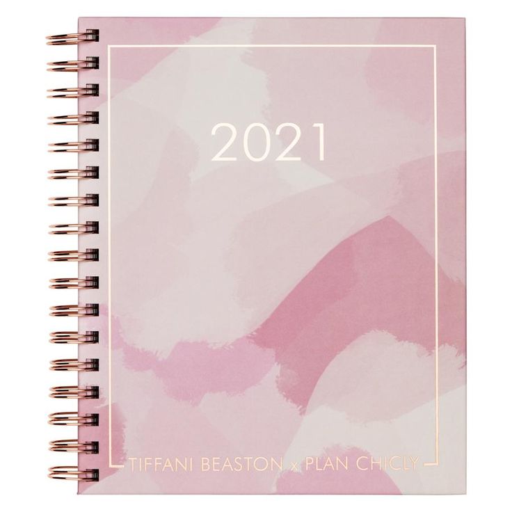 a spiral notebook with the year 2021 written in white and pink ink on a light pink background