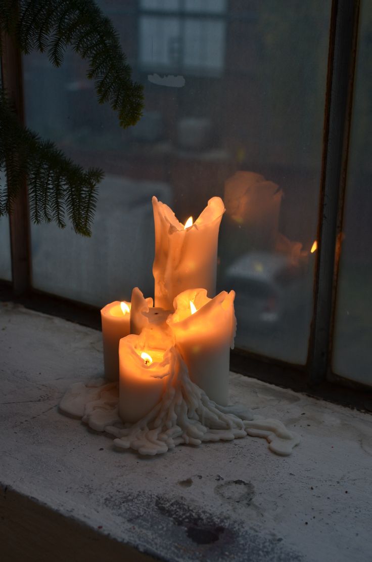 some candles that are sitting on a window sill