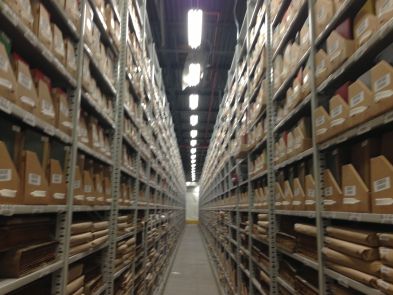 shelves filled with boxes and other items in a large warehouse or storage area at the end of an aisle