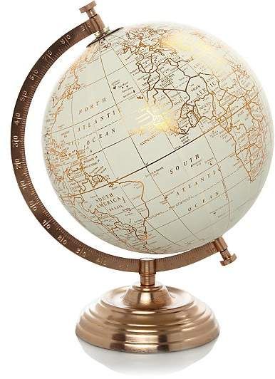 an illuminated globe on a metal stand with a white and gold color map in the center
