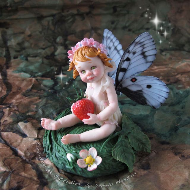 a little fairy sitting on top of a rock with a strawberry in her hand and butterfly wings