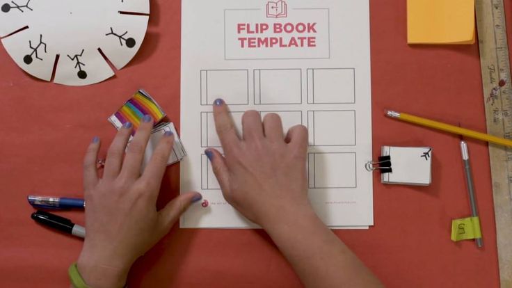 a woman's hands on top of a flip book next to markers and pencils