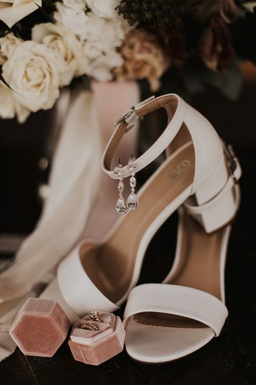 a pair of white high heeled shoes next to a bouquet