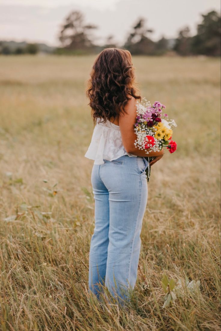 a woman standing in a field holding flowers