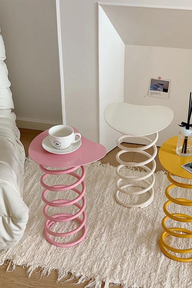 three different colored stools sitting on top of a white rug next to a bed