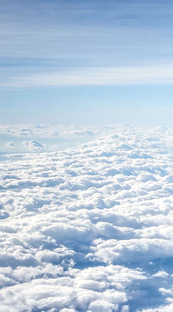 the view from an airplane looking down on clouds and blue sky with white fluffy clouds