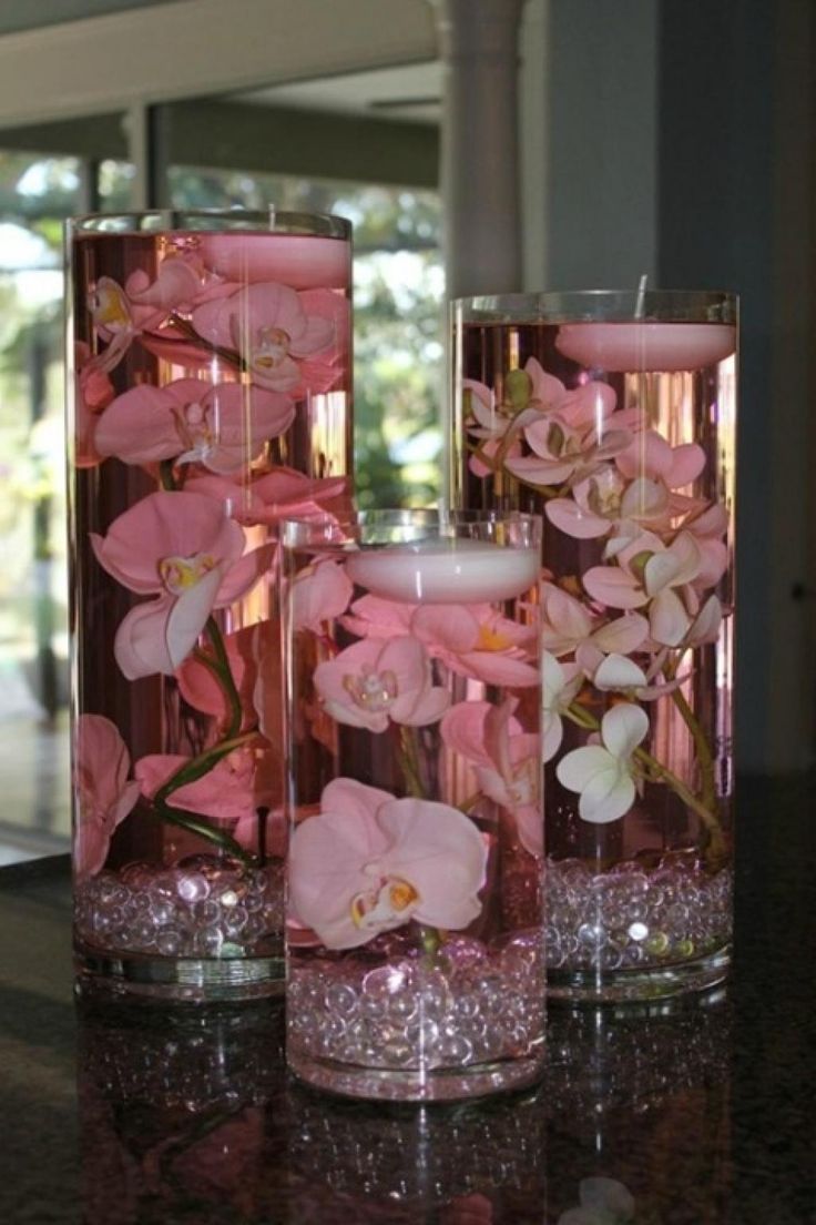 three vases filled with pink flowers on top of a table next to each other