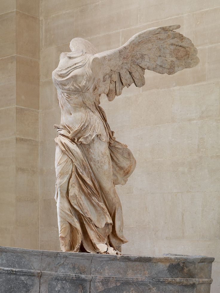 an angel statue on display in front of a wall with stone columns and walls behind it
