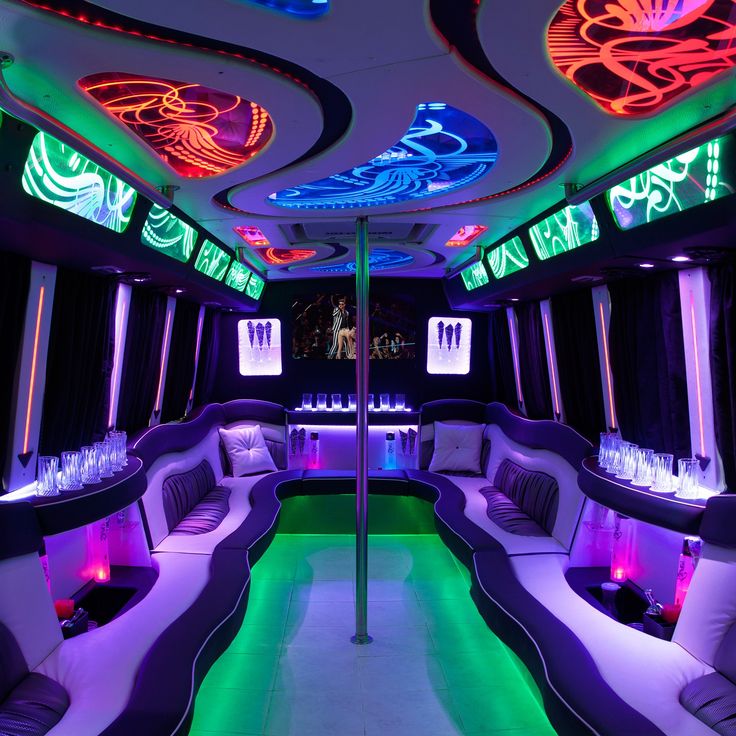 the interior of a party bus with neon lights and couches on each side,
