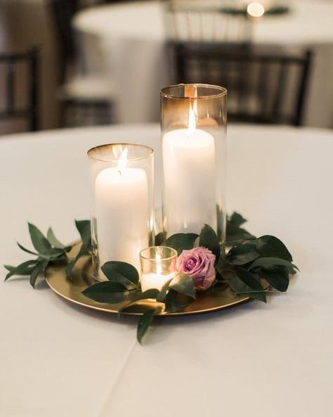 three candles are sitting on top of a plate with greenery and roses in it