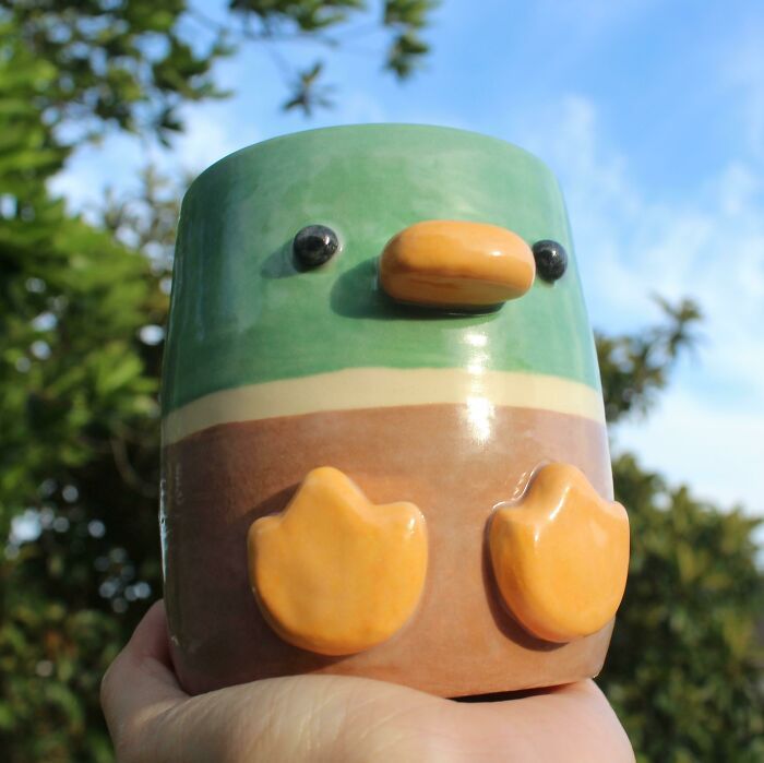 a close up of a person holding a small toy with two eyes and nose shaped like a bird