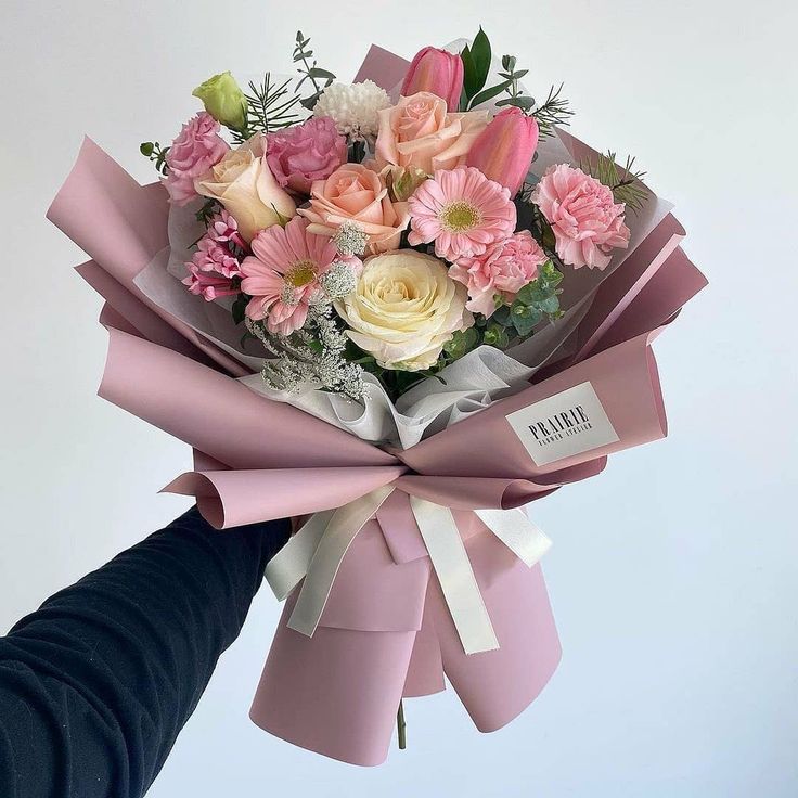 a bouquet of flowers is wrapped in pink ribbon