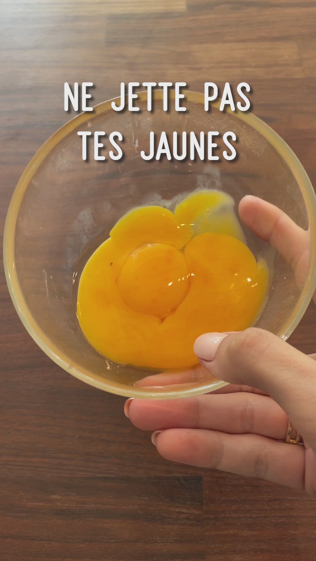 This may contain: a person holding an egg in a glass bowl with the words ne jette pas tes jaunes