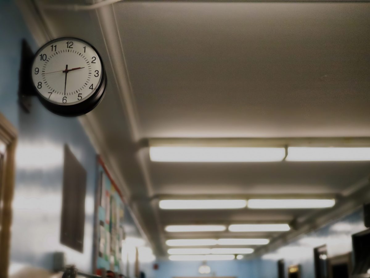 A clock is visible in the foreground of a photo in a school hallway
