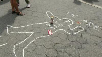 Chalk outline of person on ground and words "who is next?"