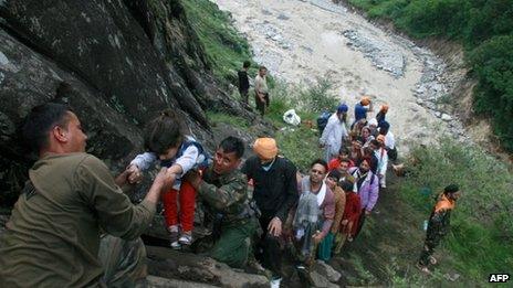 Indian army officials help travellers and villagers up a steep slope after they were stranded by the rising floodwaters of the River Alaknanda near Govindghat, Chamoli District in the northern Indian state of Uttarakhand on June 18
