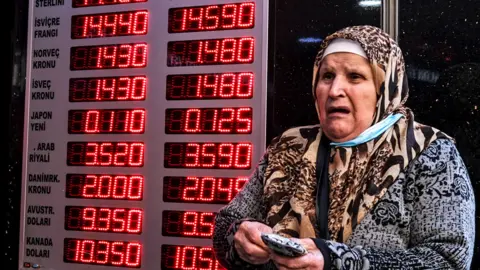 EPA A woman checks rates on a board of the currency exchange office in Istanbul, Turkey, 02 December 2021