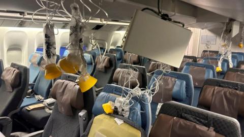 Oxygen masks and screen hanging from ceiling in Singapore Airlines plane rocked by severe turbulence