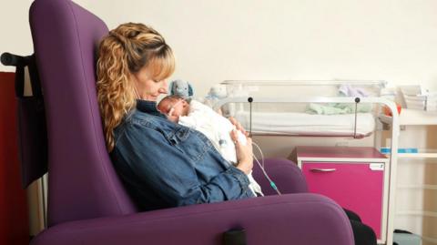 New mother Lucy Gould sitting in one of the new chairs with her new-born son