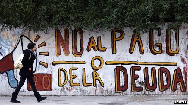 Woman walks past a graffiti that reads "No to the debt payment" in Buenos Aires, 28 July 2014