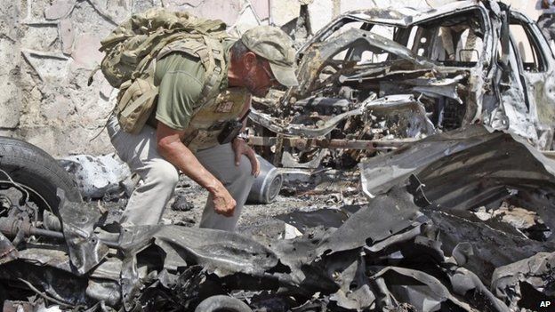 A foreign security officer inspects wreckage at the scene of a car bomb attack that targeted a United Nations convoy, outside the airport in Mogadishu, Somalia on 3 December 2014