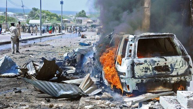 A car burns following a blast near the heavily fortified gates of the airport in Mogadishu on 3 December 2014