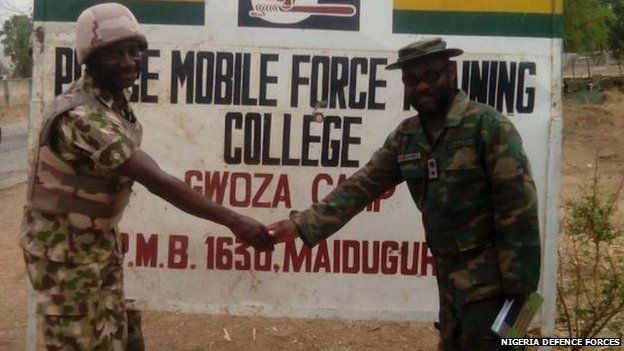 Army personnel shaking hands in front of a police training college near Gwoza