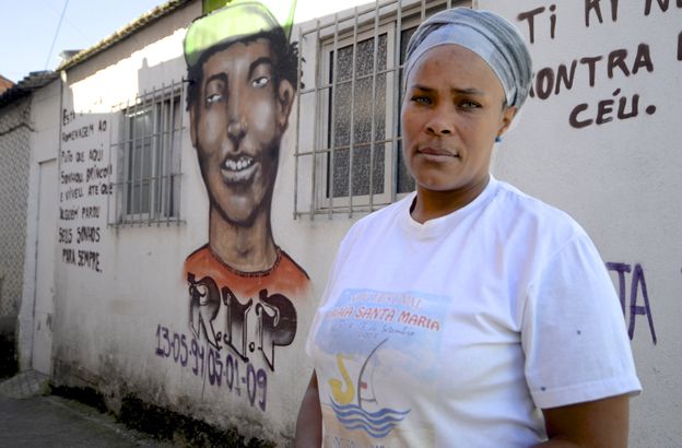 Domingas Sanches next to the picture of her son on a wall