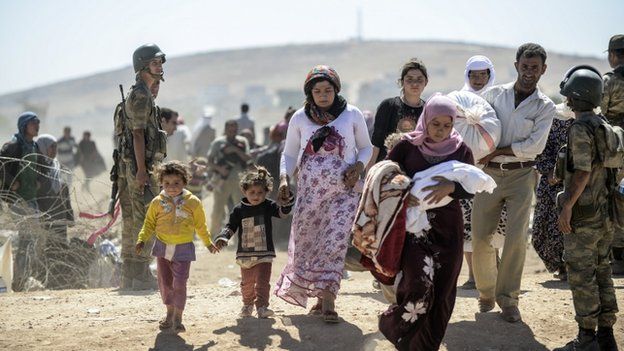 Syrian Kurd refugees pass soldiers as they cross the border from Syria into Turkey, Sanliurfa province, September 2014